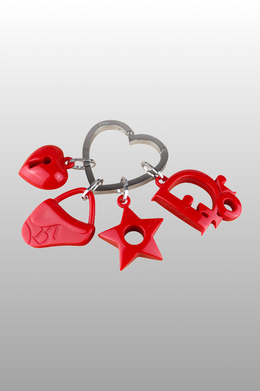A red enamel Christian Dior bag charm with heart and star shapes, featuring a metal ring for attachment.