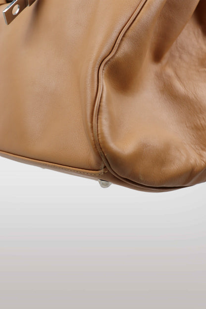 Close-up of a brown leather handbag on a light gray background