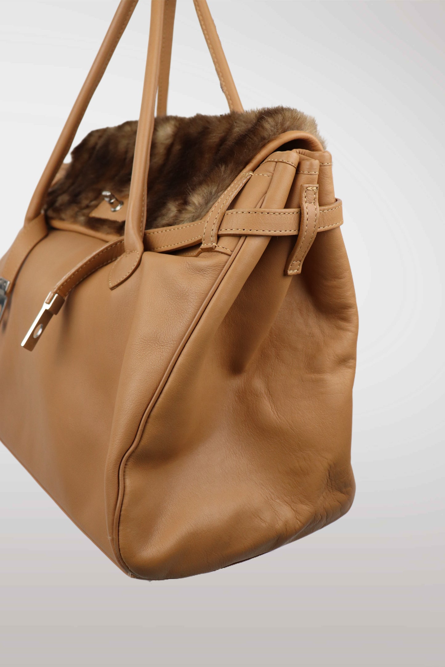 Brown handbag with fur trim on a light gray background