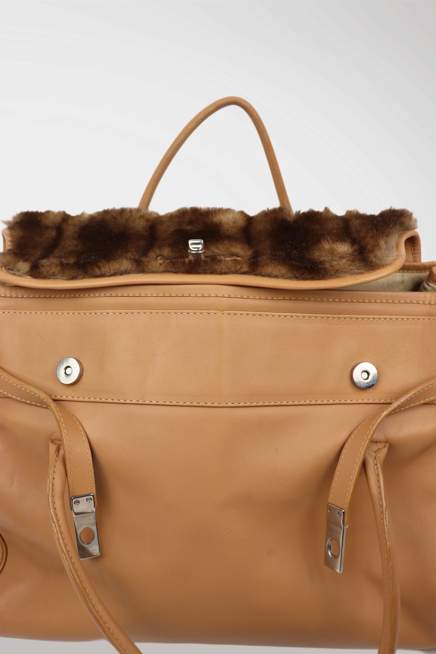 Tan leather handbag with fur trim on a white background