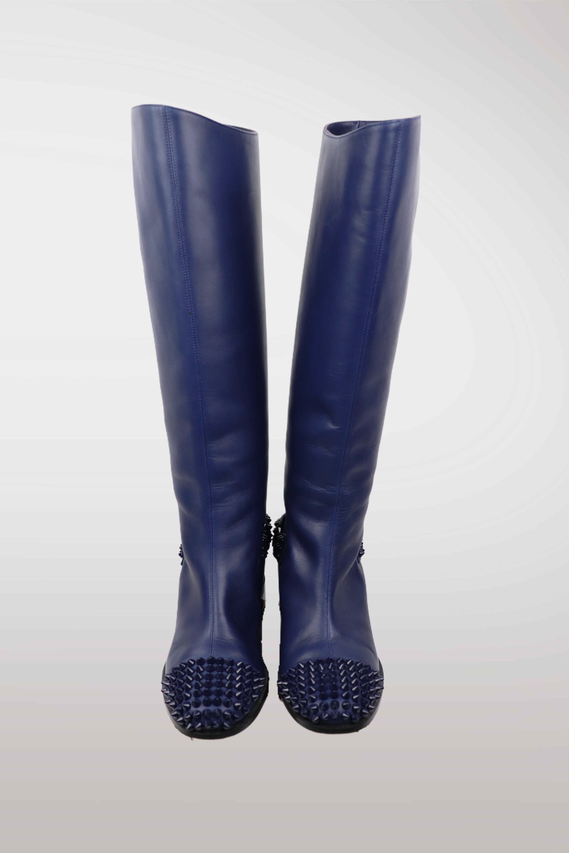 Pair of blue rubber boots with spiked soles on a white background