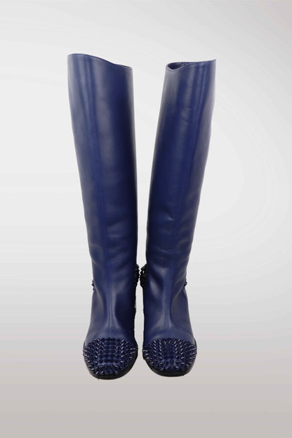 Pair of blue rubber boots with spiked soles on a white background