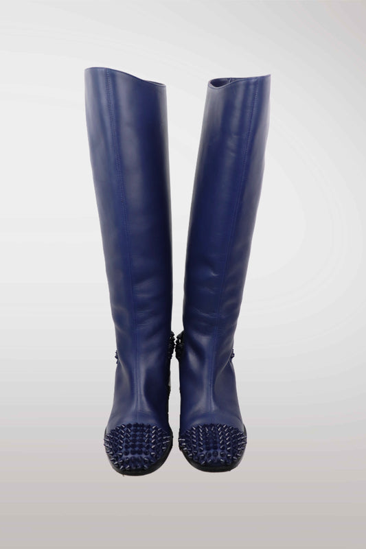 Pair of blue rubber boots with spiked soles on a white background