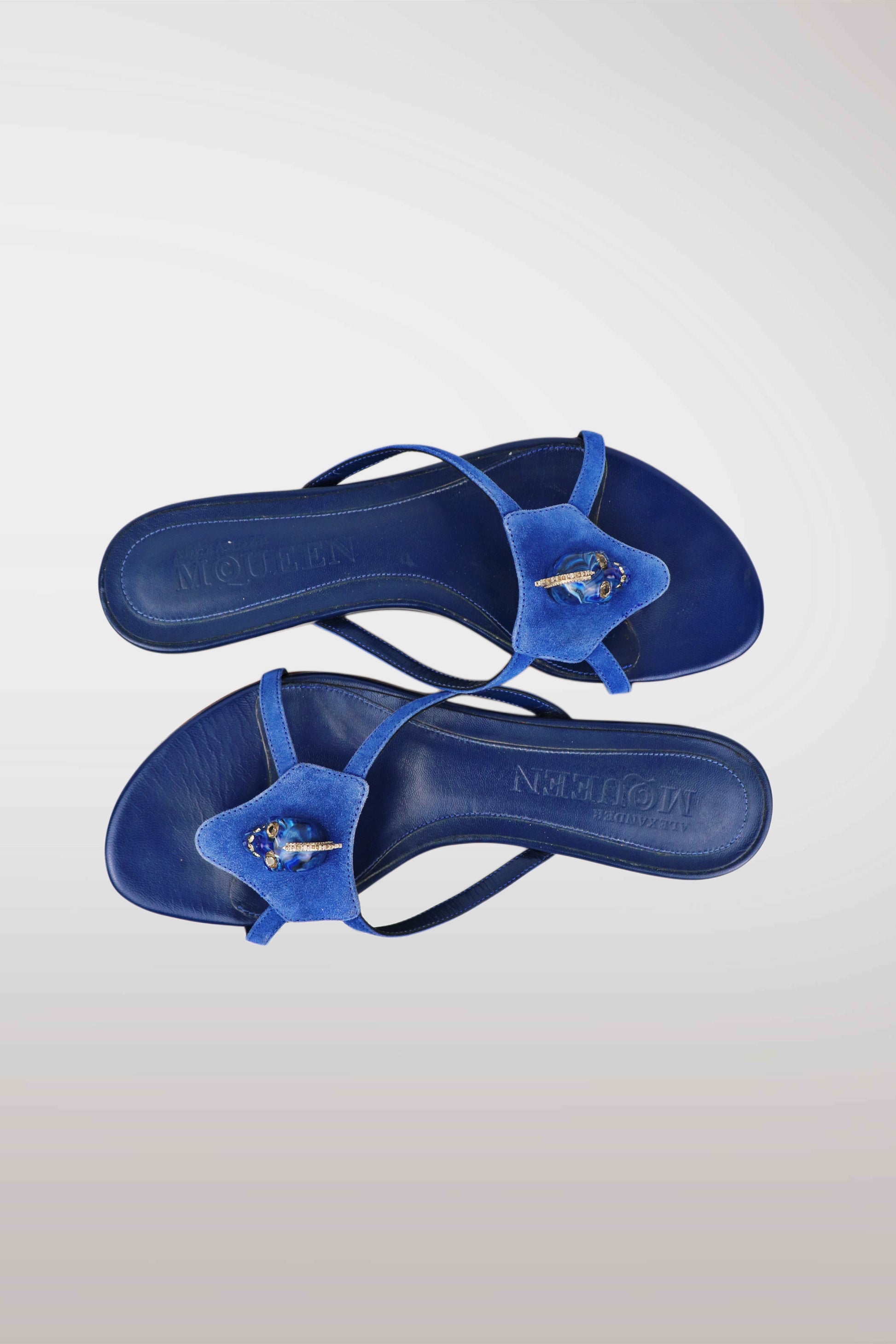 A pair of blue thong sandals with textured blue fuzzy straps and a small white and blue starfish detail, shown from a top-down view on a light gray gradient background. The brand name 'NORMAN' is embossed on the footbeds.